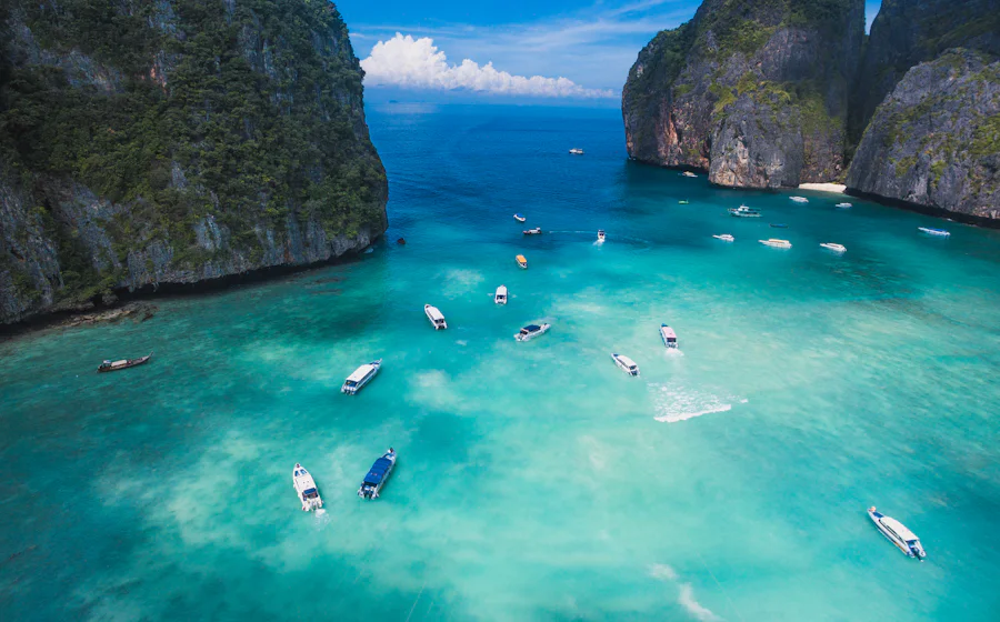 Boats on turquoise water between limestone cliffs in Maya Bay, Thailand