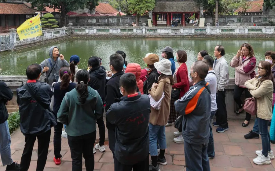 A tour group listening to a guide beside a pond at a historic site